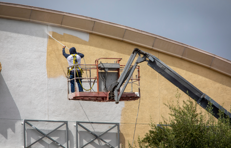 Professional painters applying fresh coat of paint to a commercial building exterior.