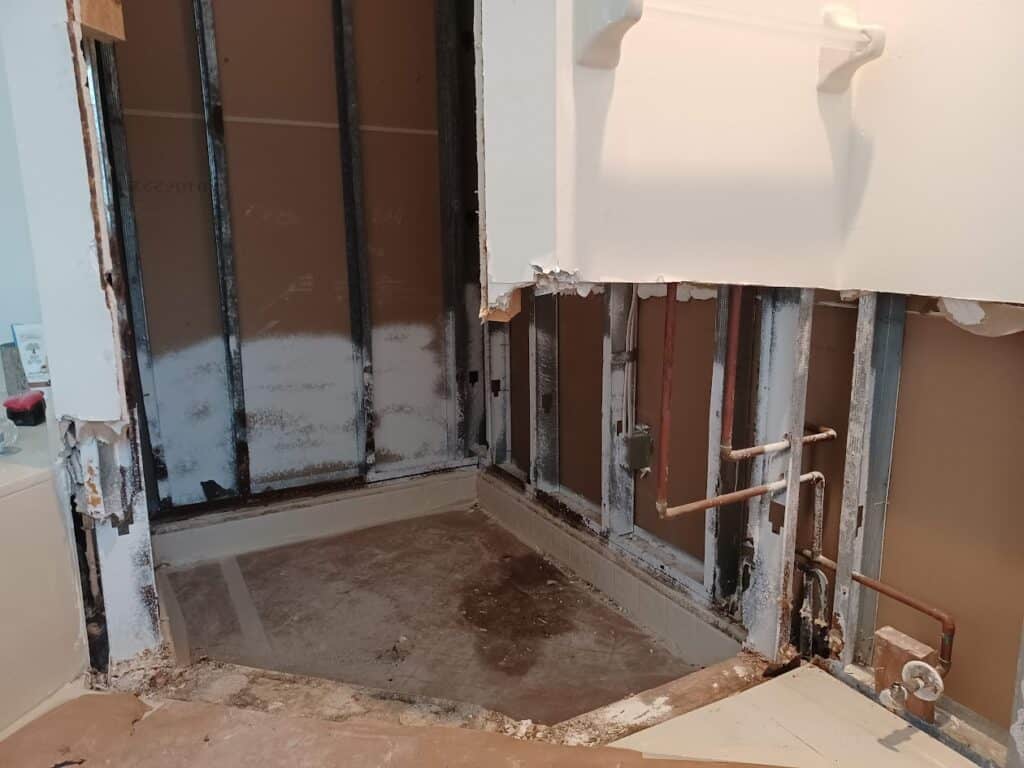 Before water damage repair in bathroom at a home in Palm Bay FL showing cut out drywall
